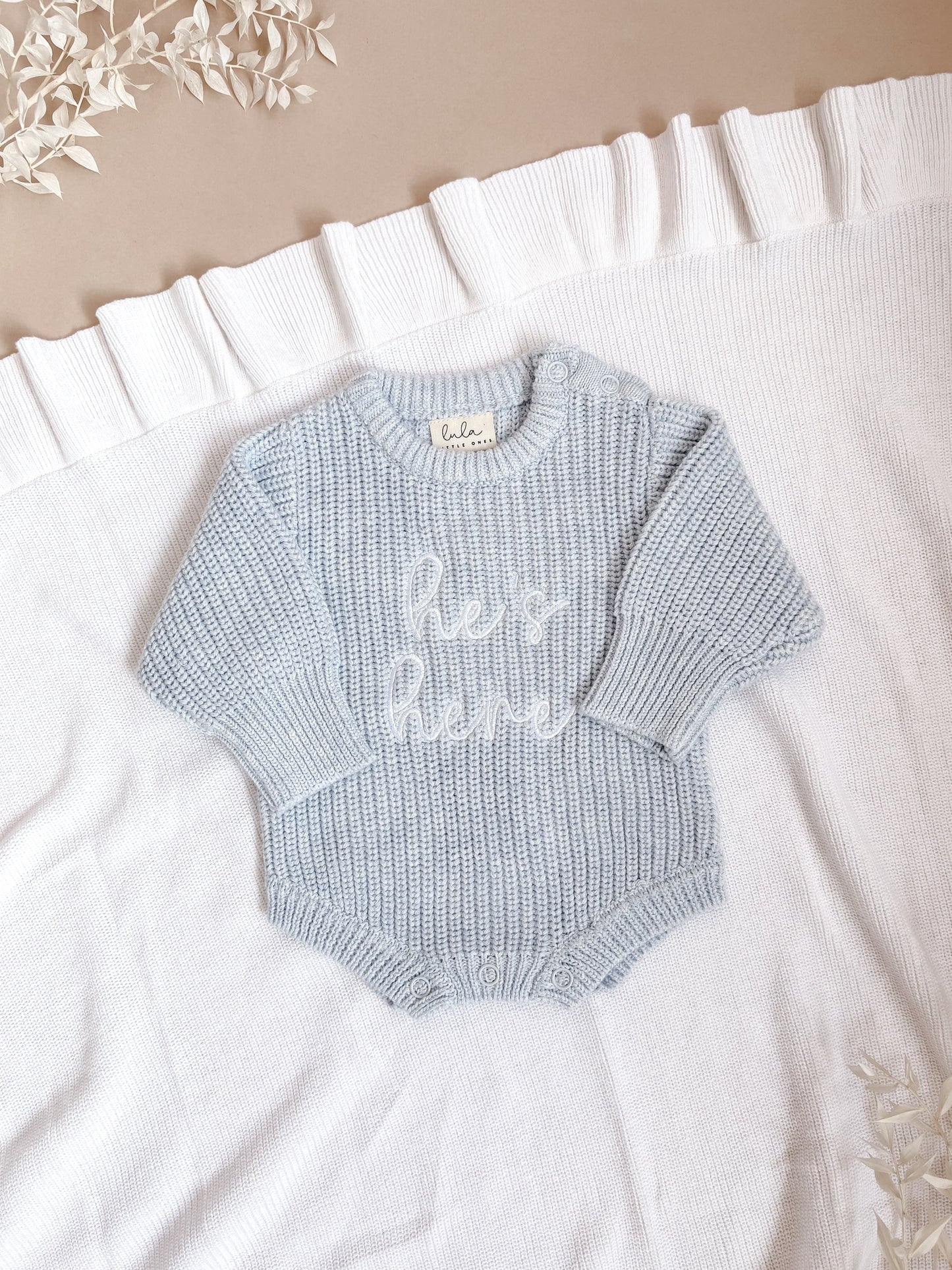 Light blue baby romper with 'He's here' embroidery in white thread