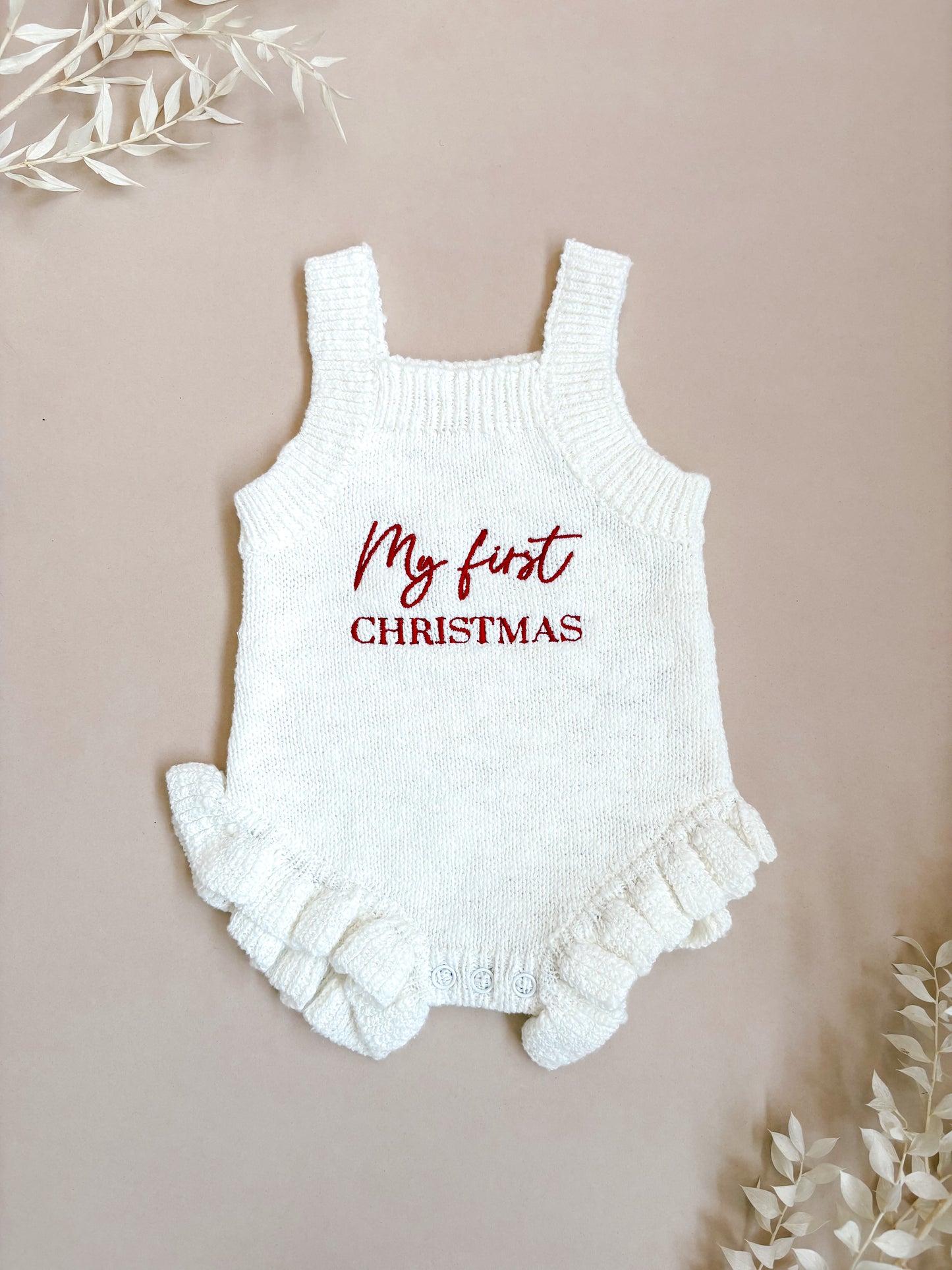 White baby romper with 'My first Christmas' text on a beige background