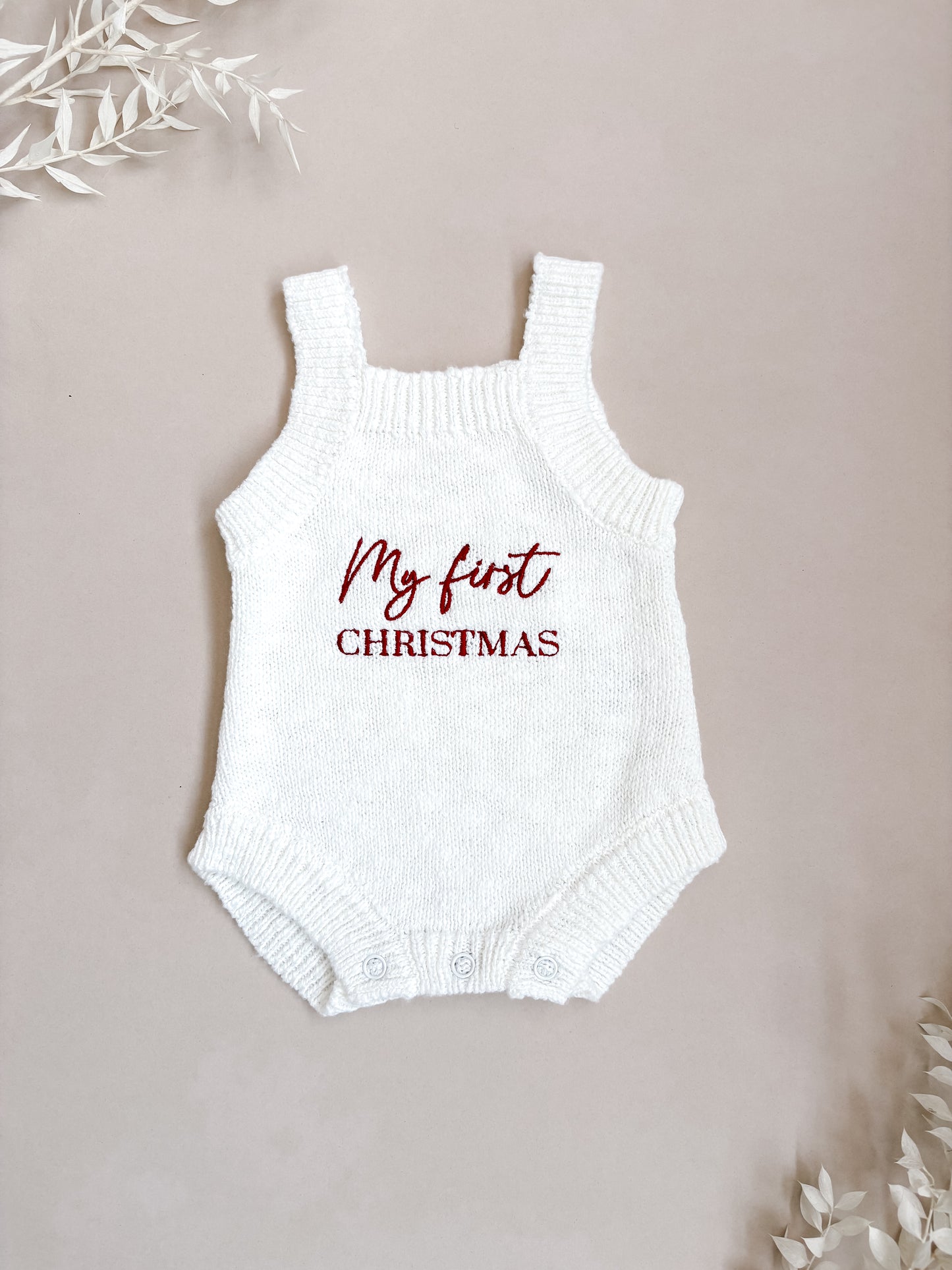 White baby romper with 'My first Christmas' text on a beige background