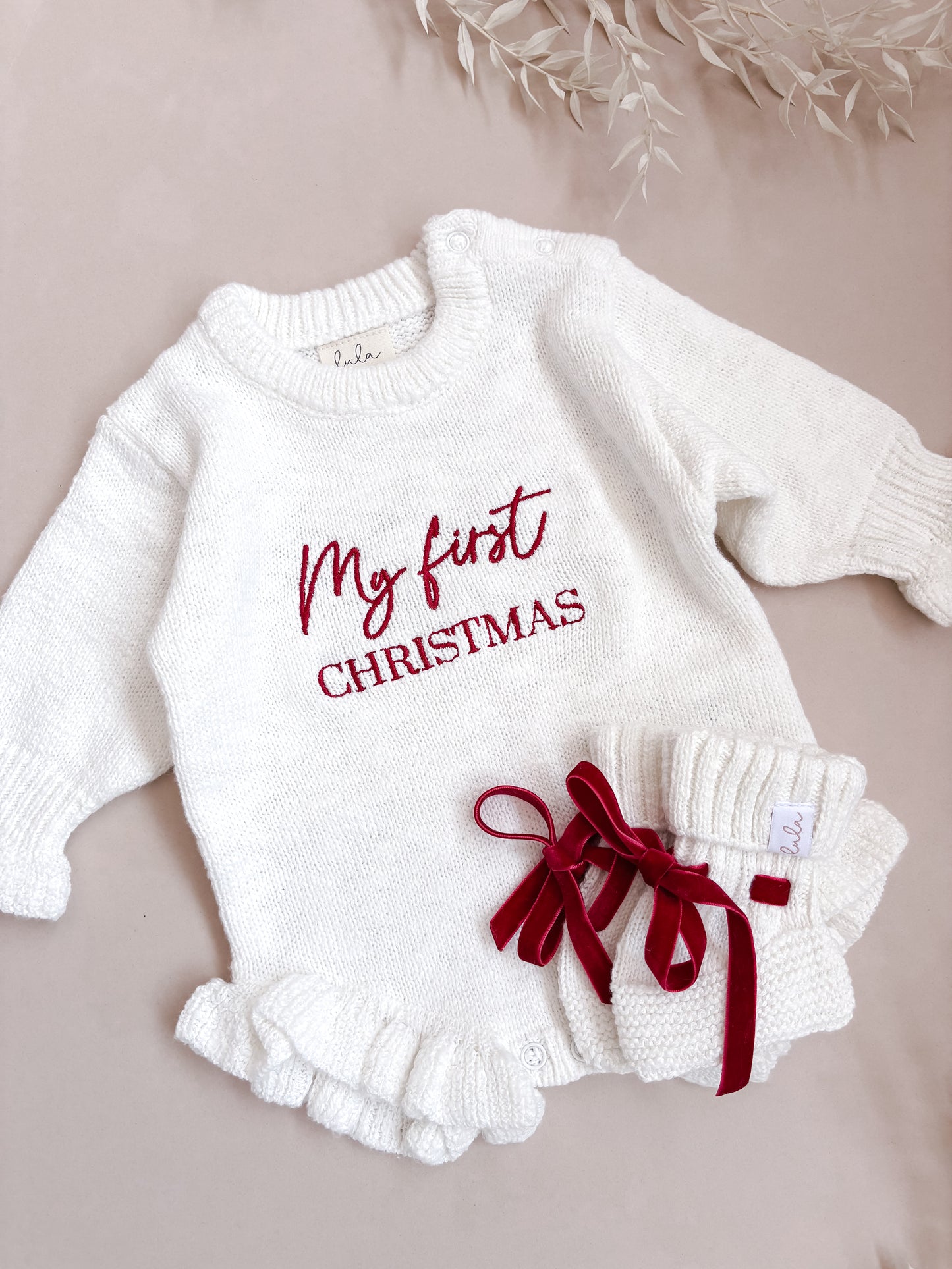 Baby outfit with 'My first Christmas' text on a beige background