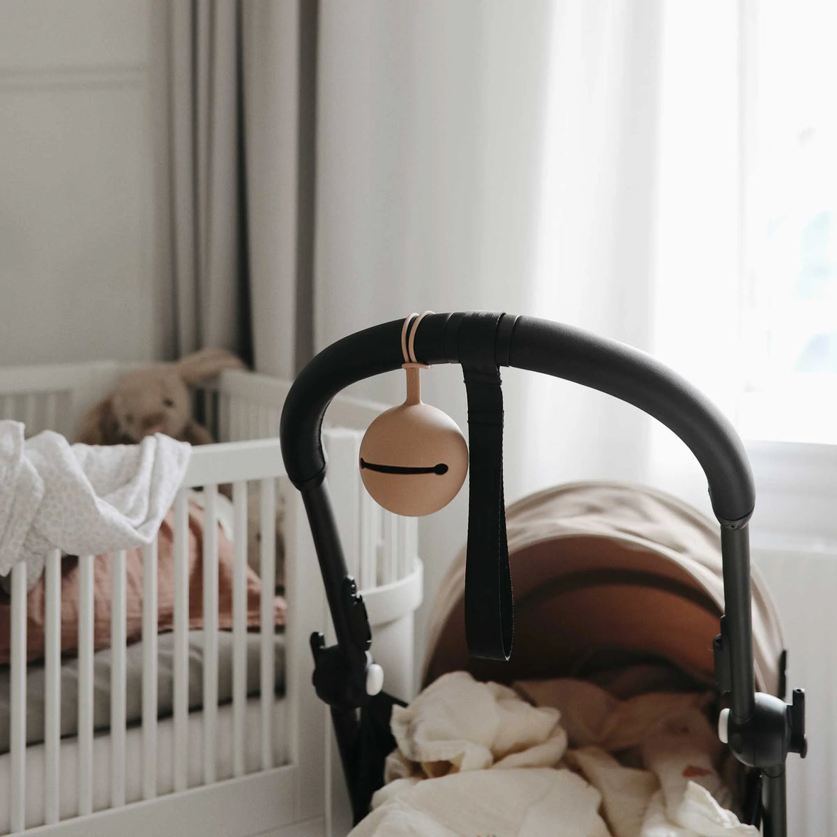 Mushie Dummy Case - Pale Taupe attached to a pram