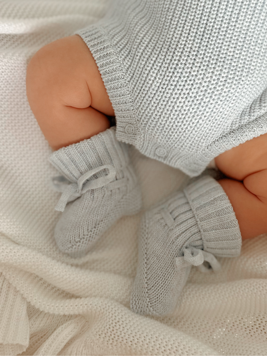 Close-up of a baby's legs wearing blue knitted booties.