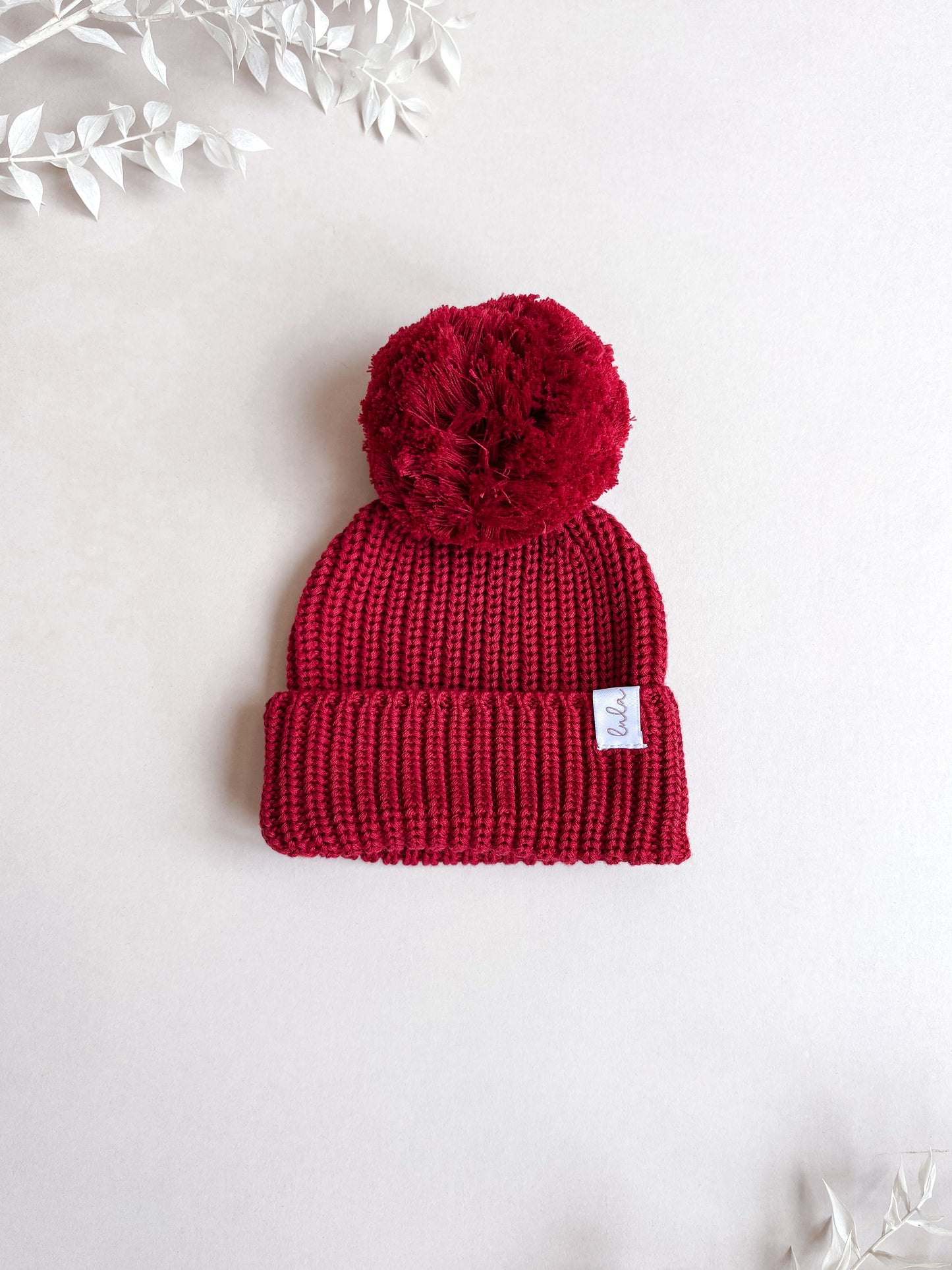 red knitted baby hat with pom pom