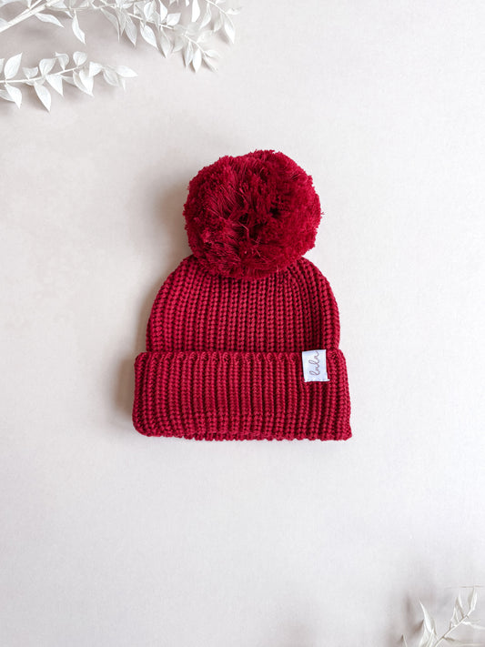 red knitted baby hat with pom pom