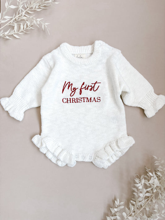 White baby romper with 'My first Christmas' text on a beige background