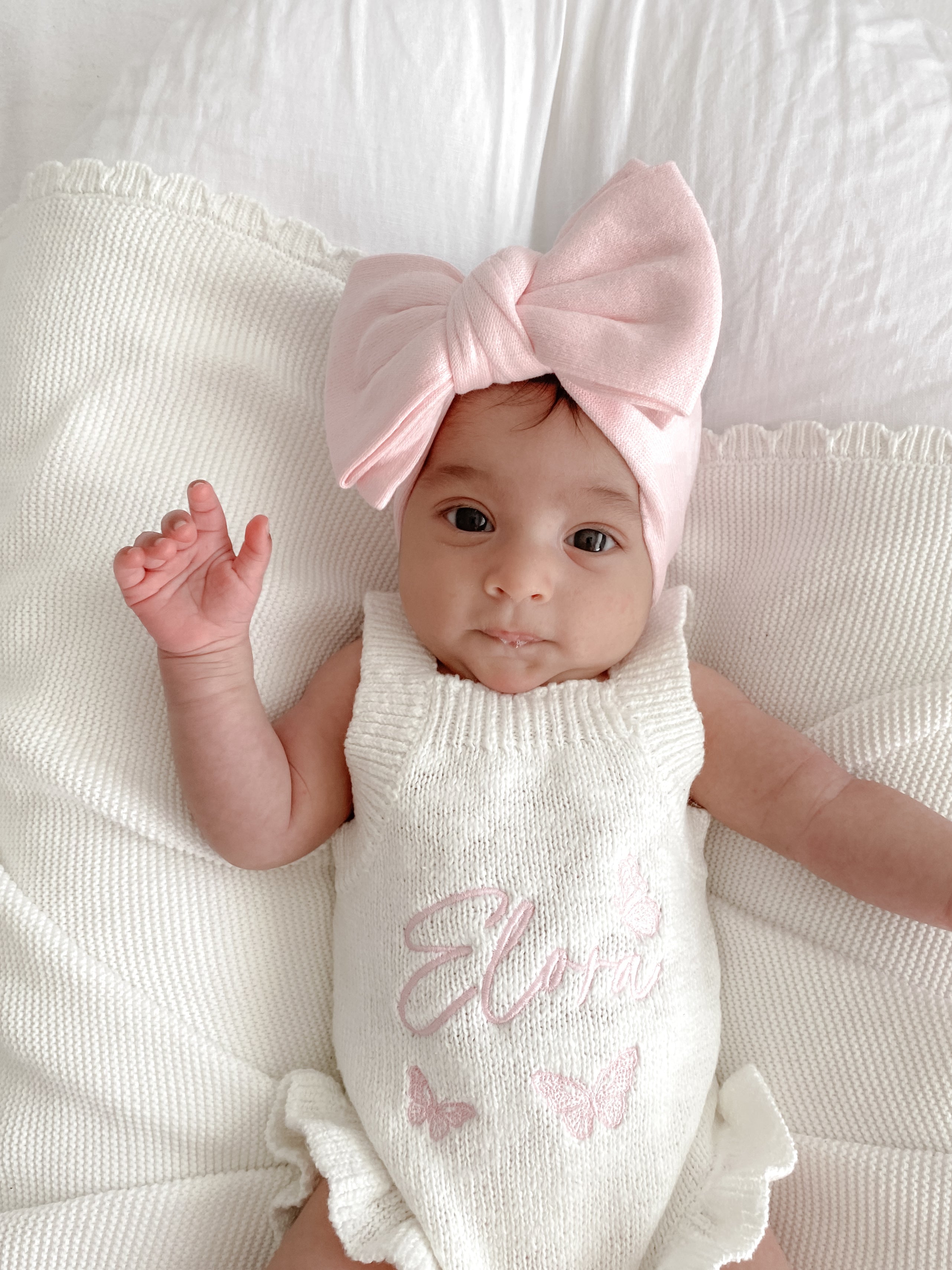 baby girl wearing a pink bow headband and frill romper